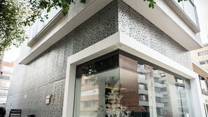A modern building with a textured facade, large glass windows, and a bench outside. - GIO Hotel CITYFLATS Collection Bogotá (Bogotá)