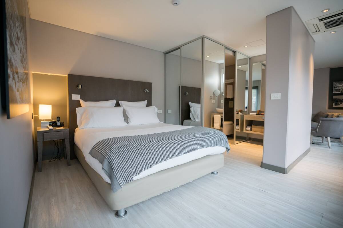 Une chambre d’hôtel moderne avec un grand lit, une table de chevet avec une lampe et un miroir.