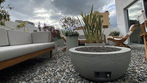 A rooftop terrace with a stone fire pit, seating area, and potted plants. - GIO Hotel CITYFLATS Collection Bogotá (Bogotá)