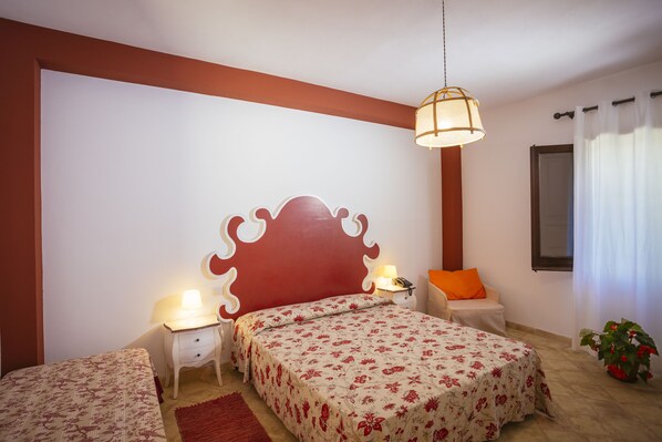 A bedroom with a large bed, two bedside tables, a nightstand, a lamp, a window with curtains, and a potted plant. - Hotel Baglio Catalano (Custonaci)