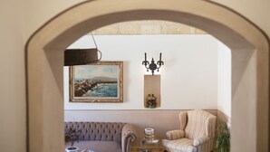 A cozy living room with a sofa, armchair, and a painting on the wall. - Hotel Baglio Catalano (Custonaci)