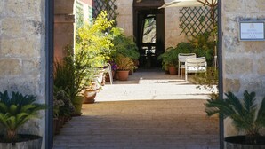 An arched entrance with a metal gate, potted plants, and a sign for Hotel Rigo Català. - Hotel Baglio Catalano (Custonaci)