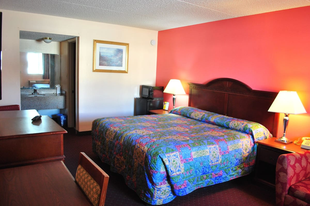 Une chambre d’hôtel avec un lit, des lampes de chevet, un bureau et une chaise.