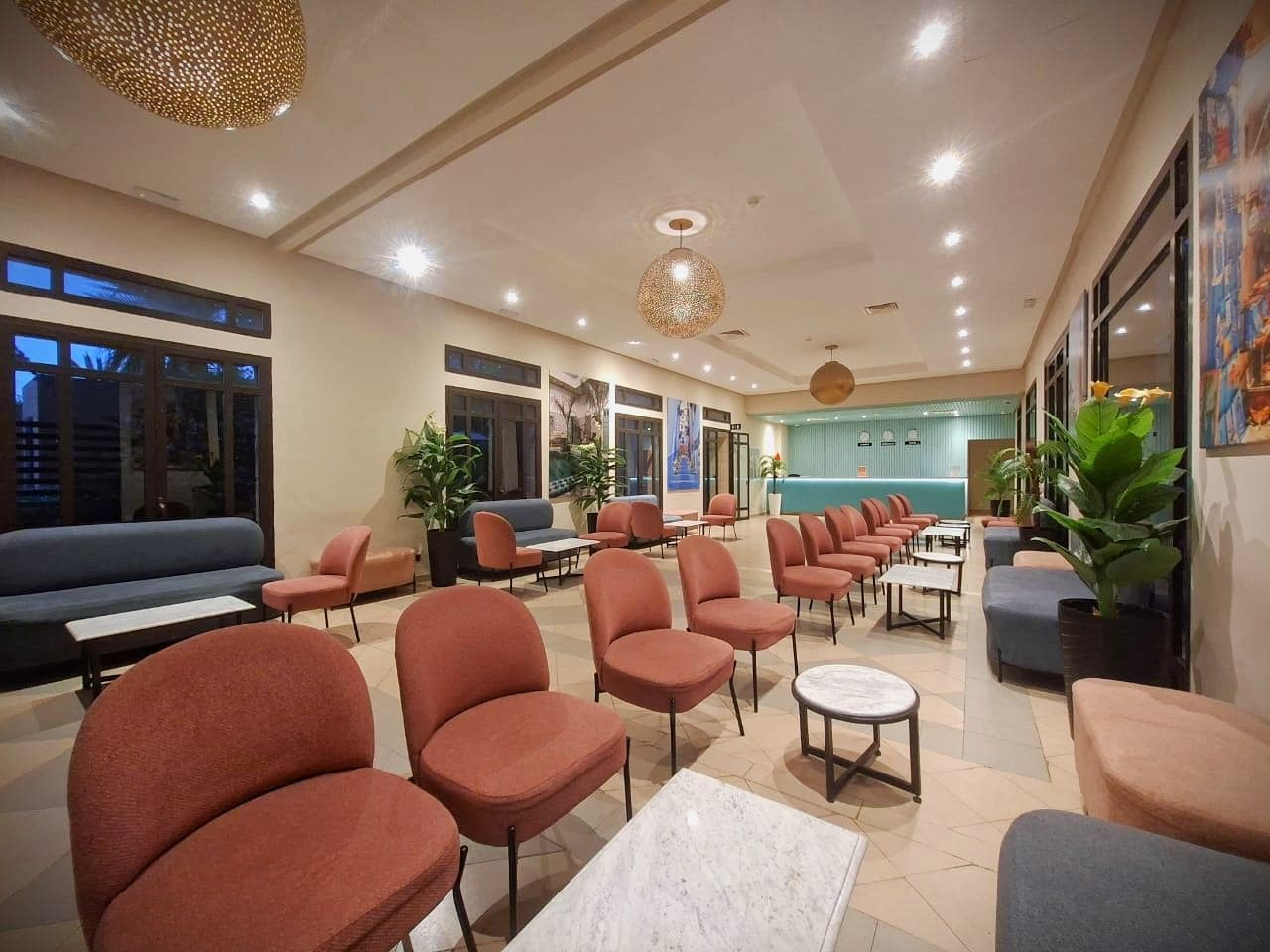 A hotel lobby with multiple seating areas, including sofas and chairs, and a reception desk.