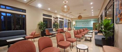 A hotel lobby with multiple seating areas, including sofas and chairs, and a reception desk.