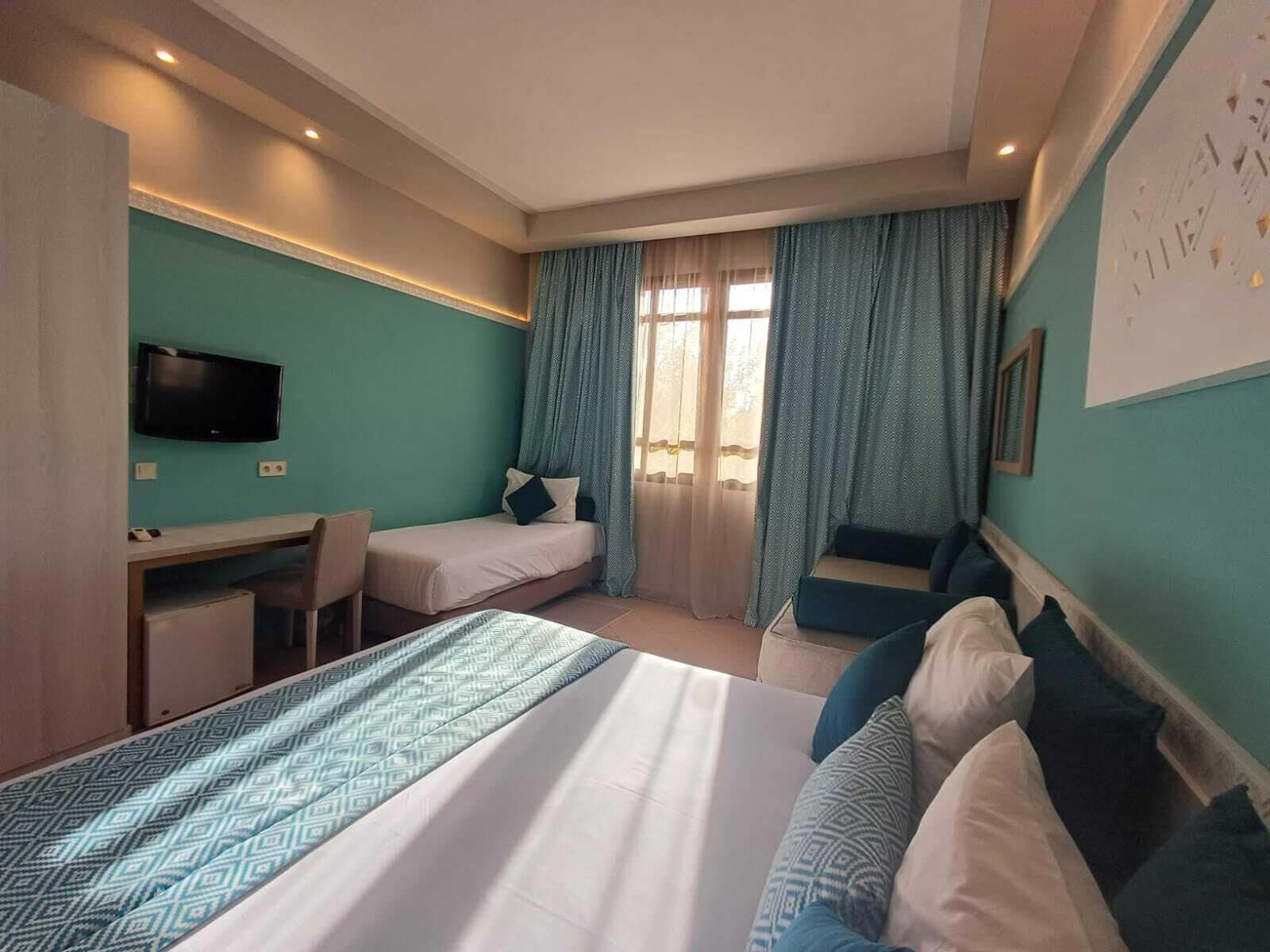 A hotel room with a bed, a desk, a chair, and a television.