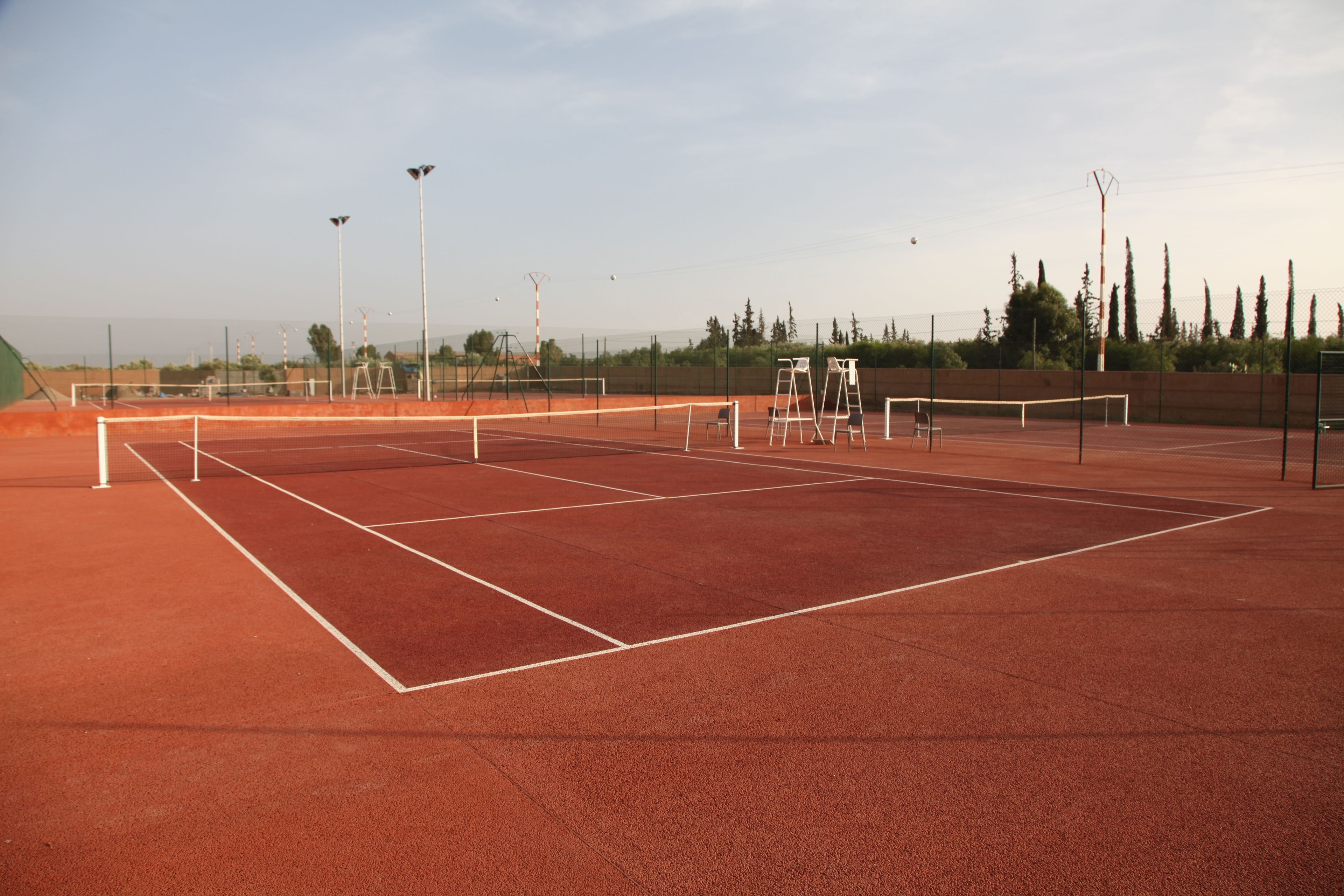 Una cancha de tenis con red, líneas delimitadoras blancas e iluminación artificial.
