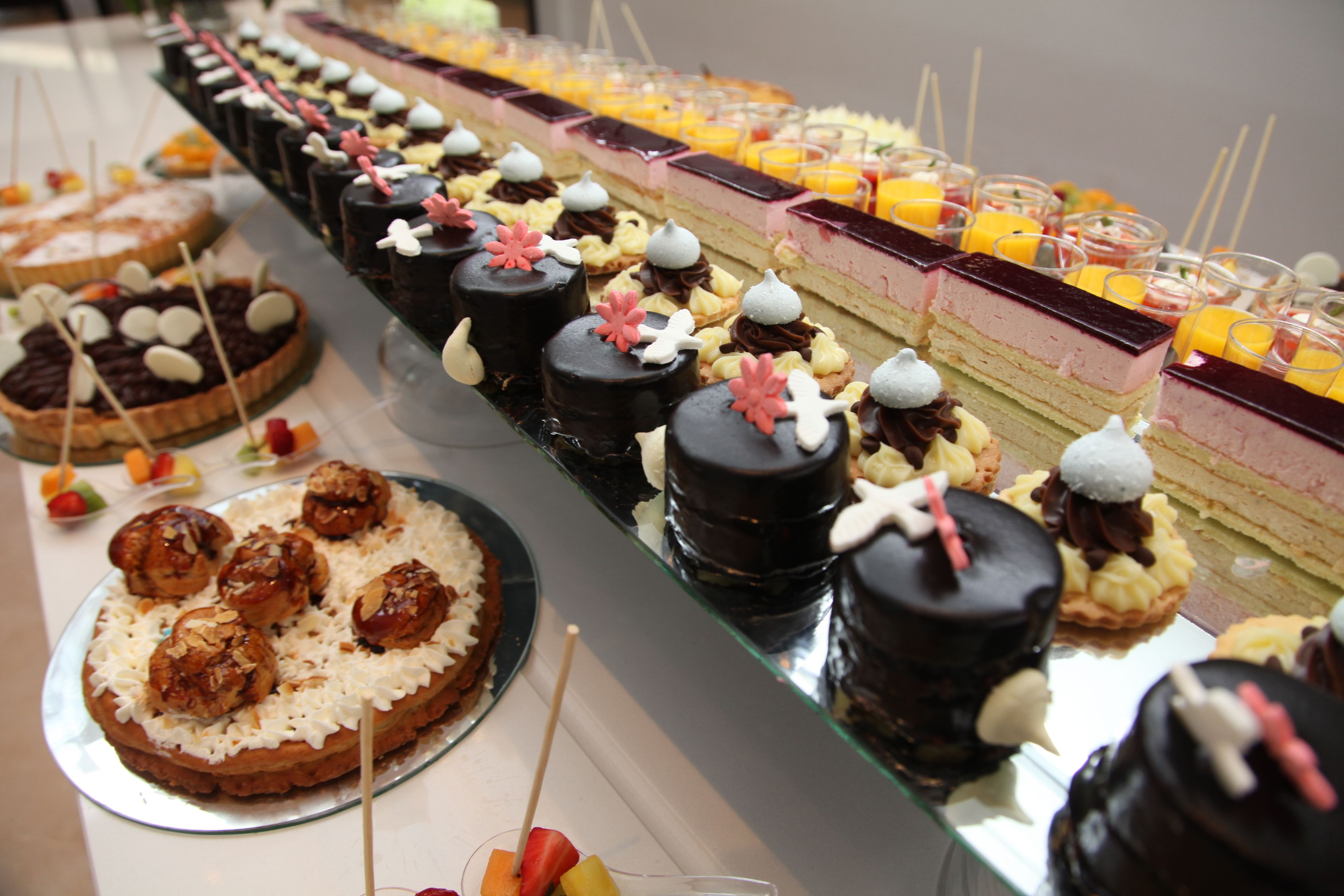 Un buffet proposant une variété de desserts et d’en-cas, notamment des gâteaux, des pâtisseries et des fruits.