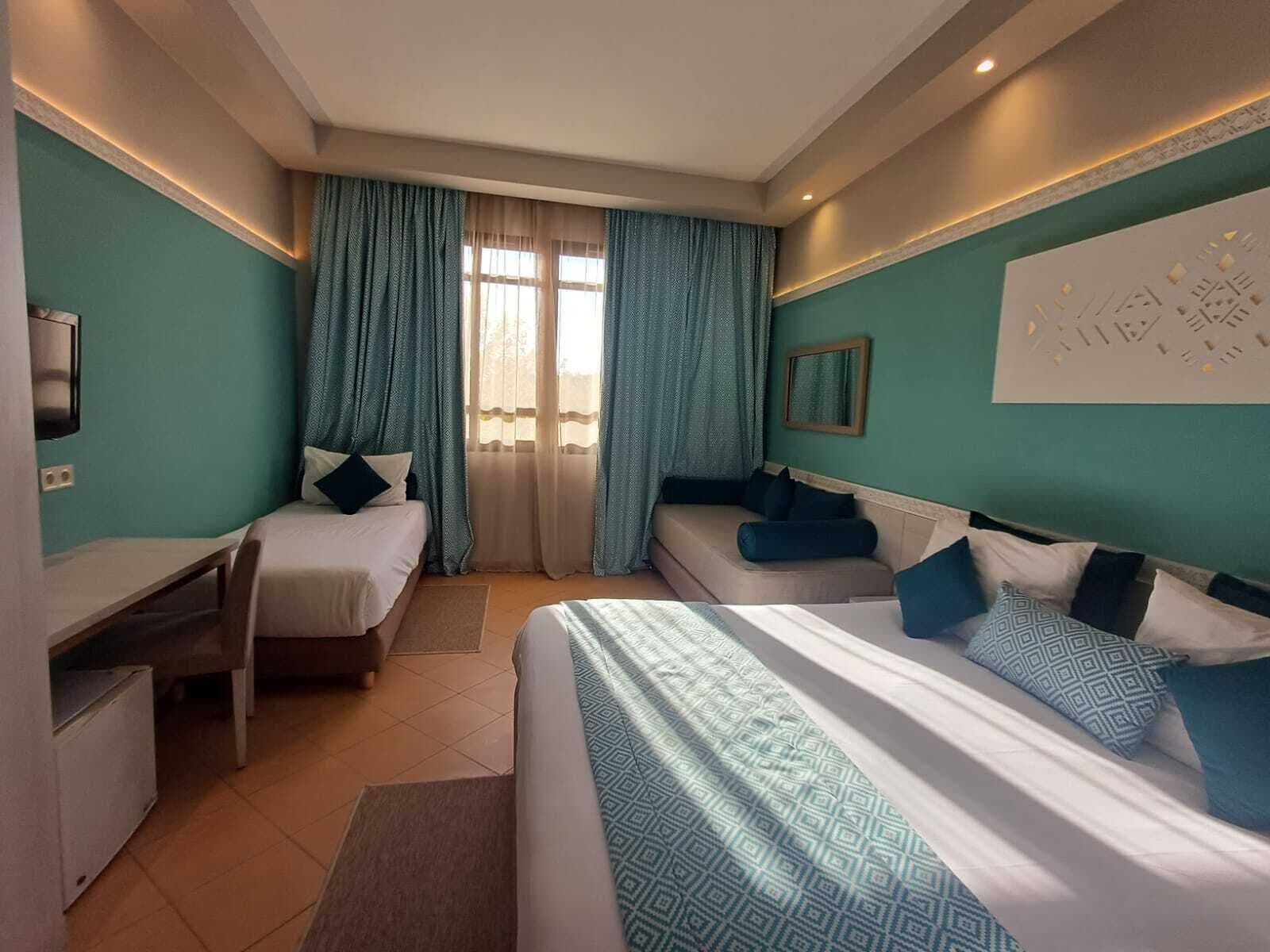 Habitación de hotel con dos camas, un escritorio y un sofá.