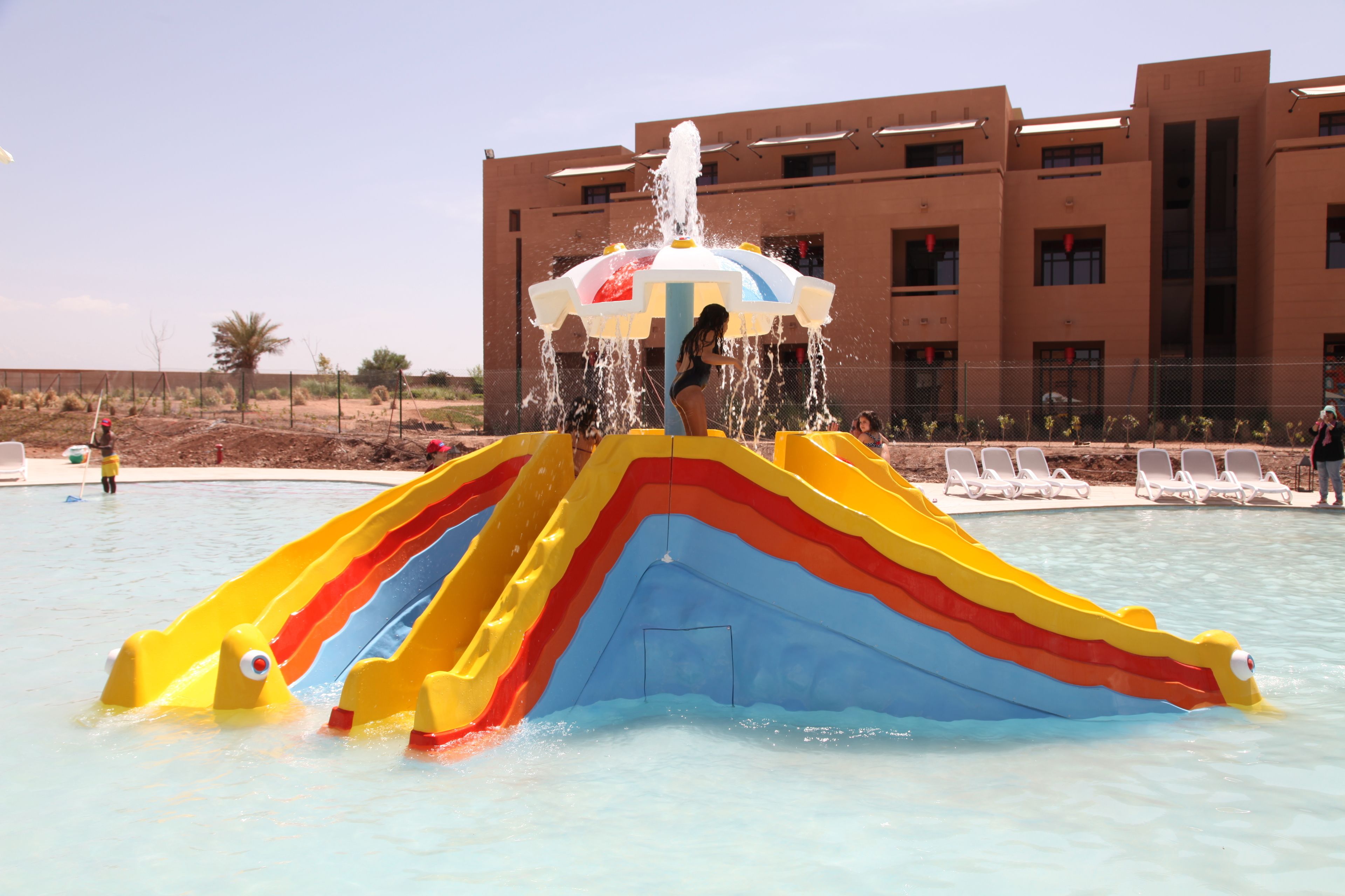 Ein Wasserspielplatz mit einer bunten Rutsche und einer Fontäne.