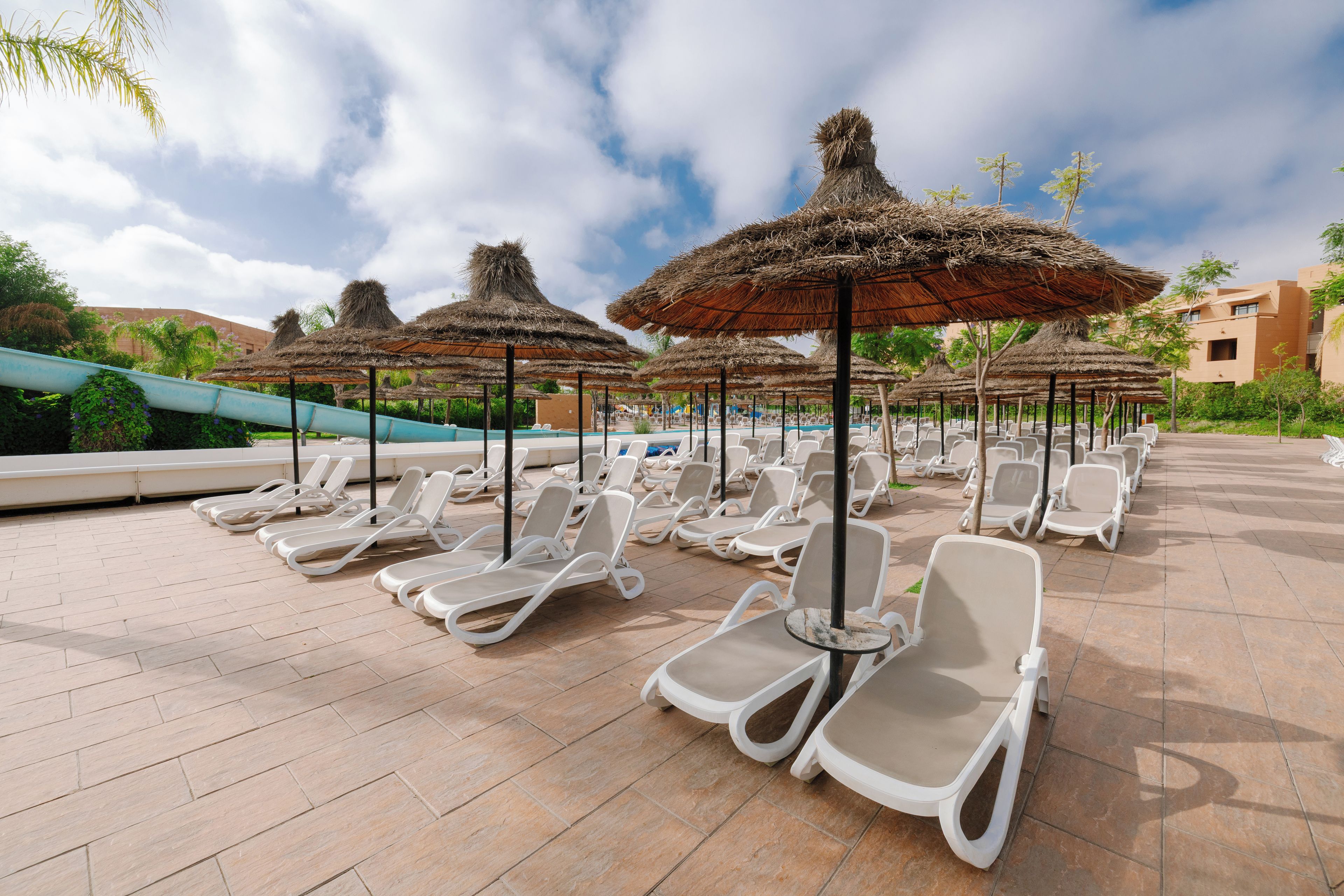 A poolside area with lounge chairs and thatched umbrellas.