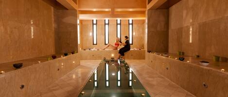 A spa area with a central pool, benches, and candles.