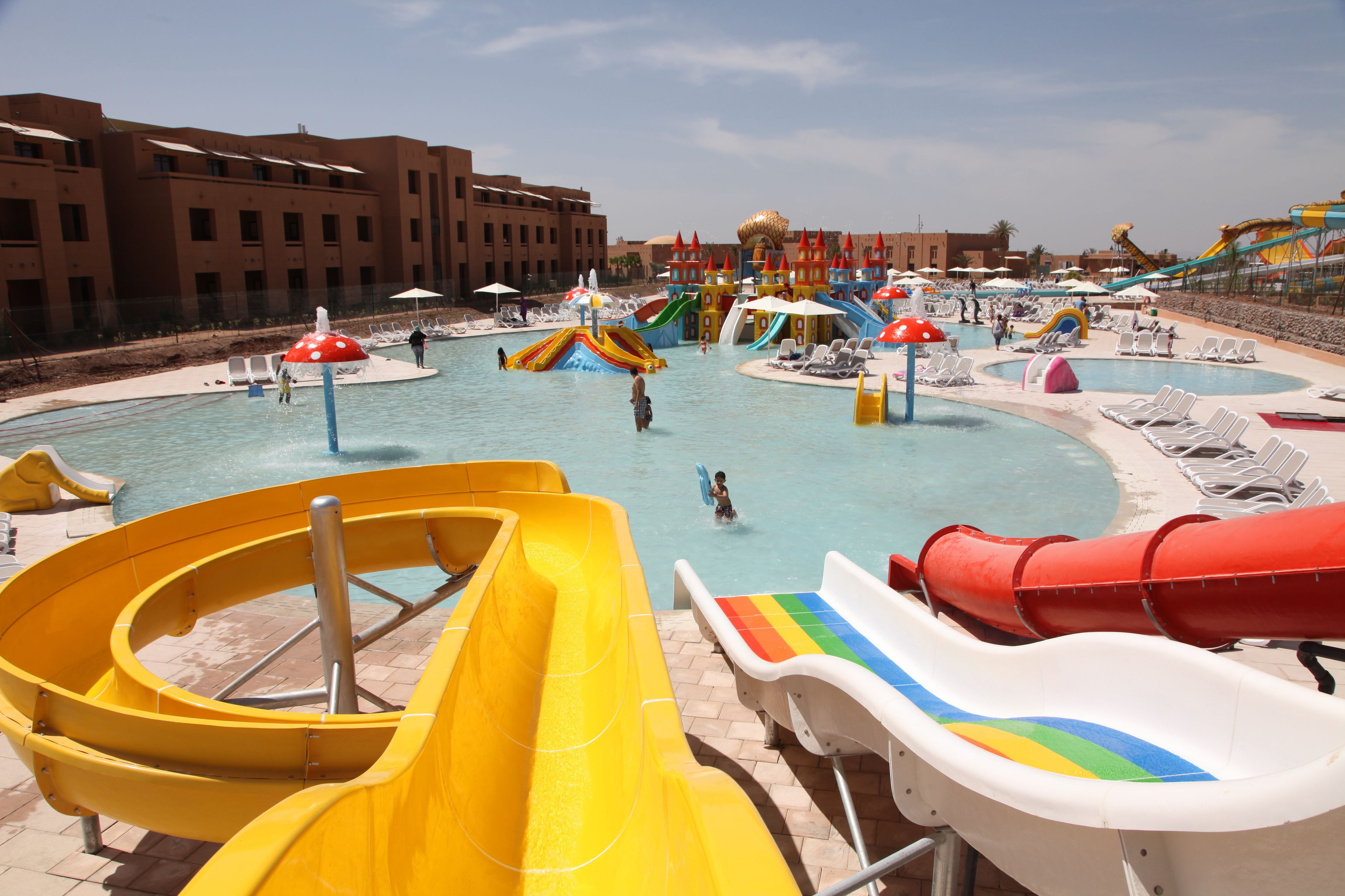 Un parc aquatique doté de nombreux toboggans et de plusieurs piscines, entouré de chaises longues et de parasols.