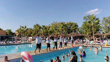 A swimming pool with people engaging in water activities and a group performing a synchronized exercise routine.