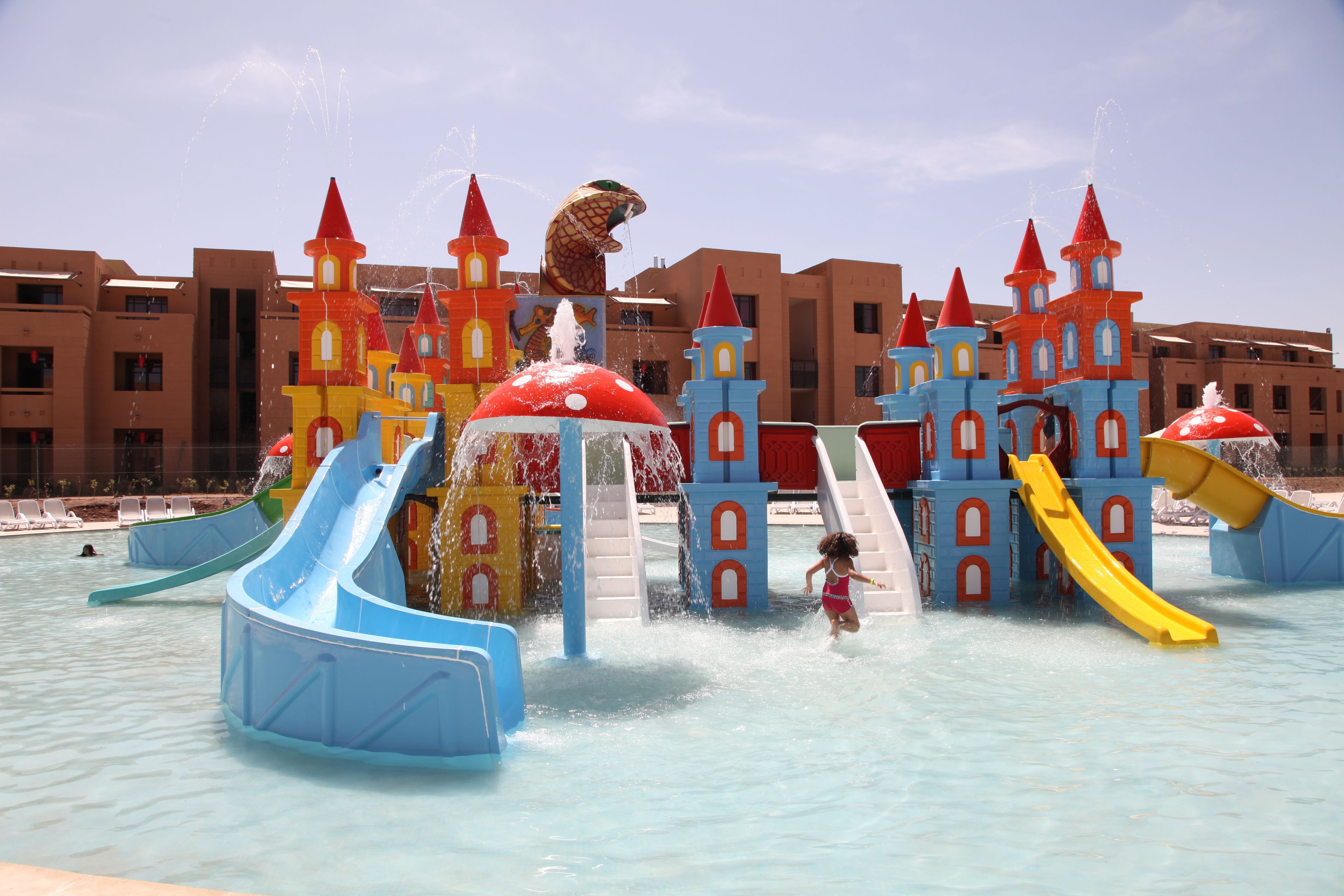 Um parque aquático com vários toboáguas e atrações aquáticas, incluindo uma estrutura que lembra um castelo e uma grande escultura de pássaro.