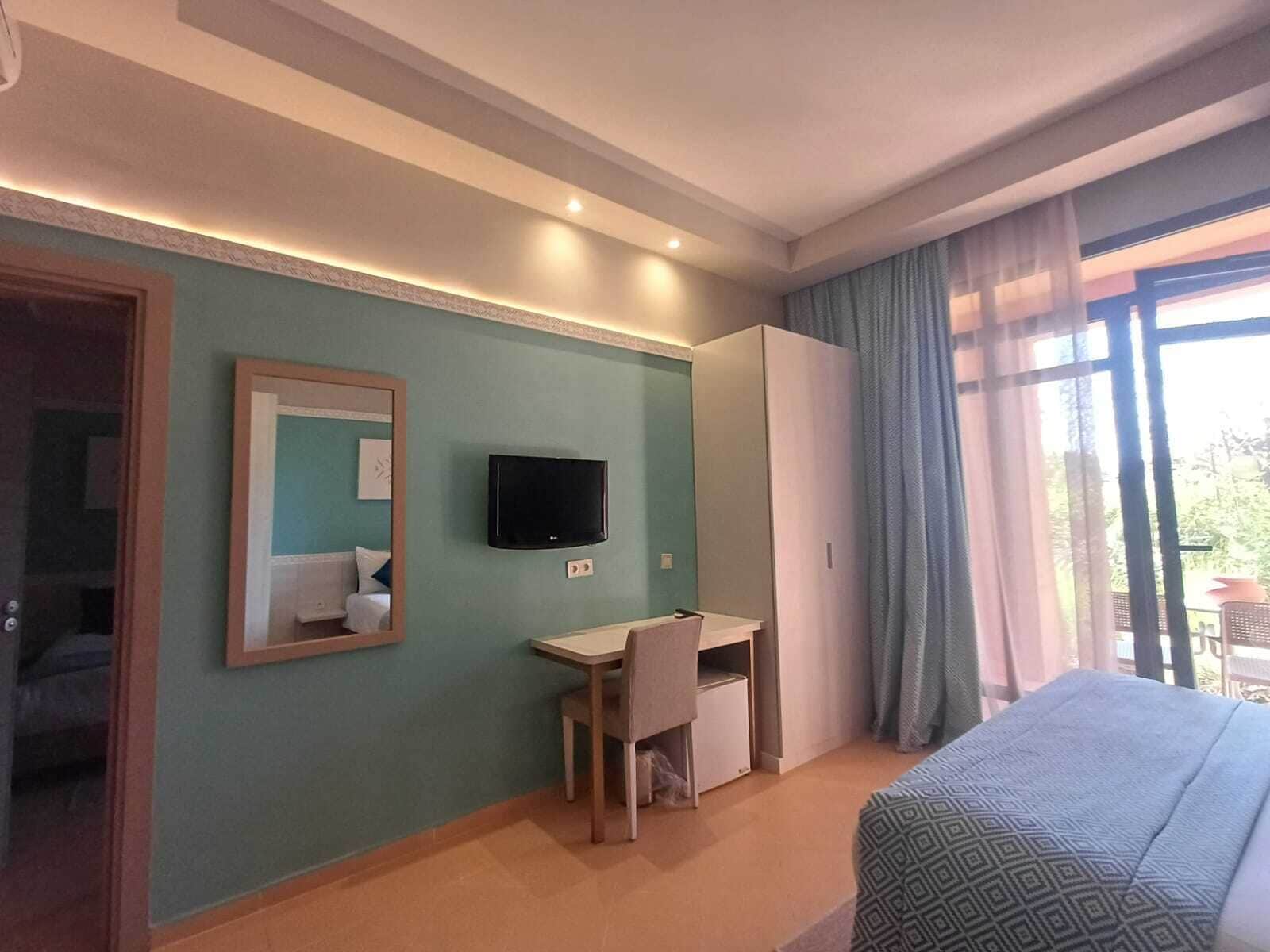 Een hotelkamer met een bed, een bureau, een televisie en een kledingkast.