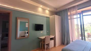 Een hotelkamer met een bed, een bureau, een televisie en een kledingkast.