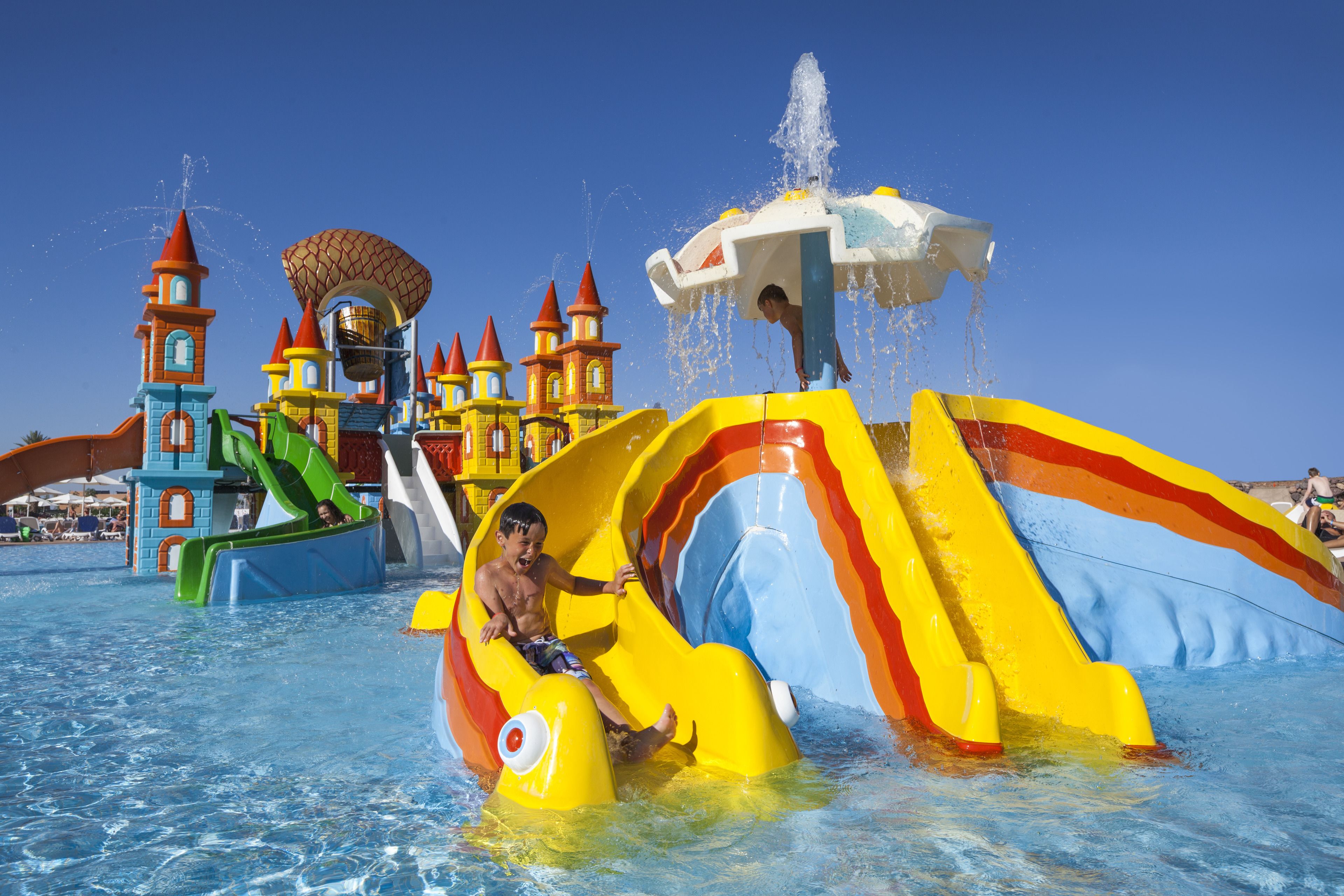 A water park with a large slide and a castle-like structure in the background.