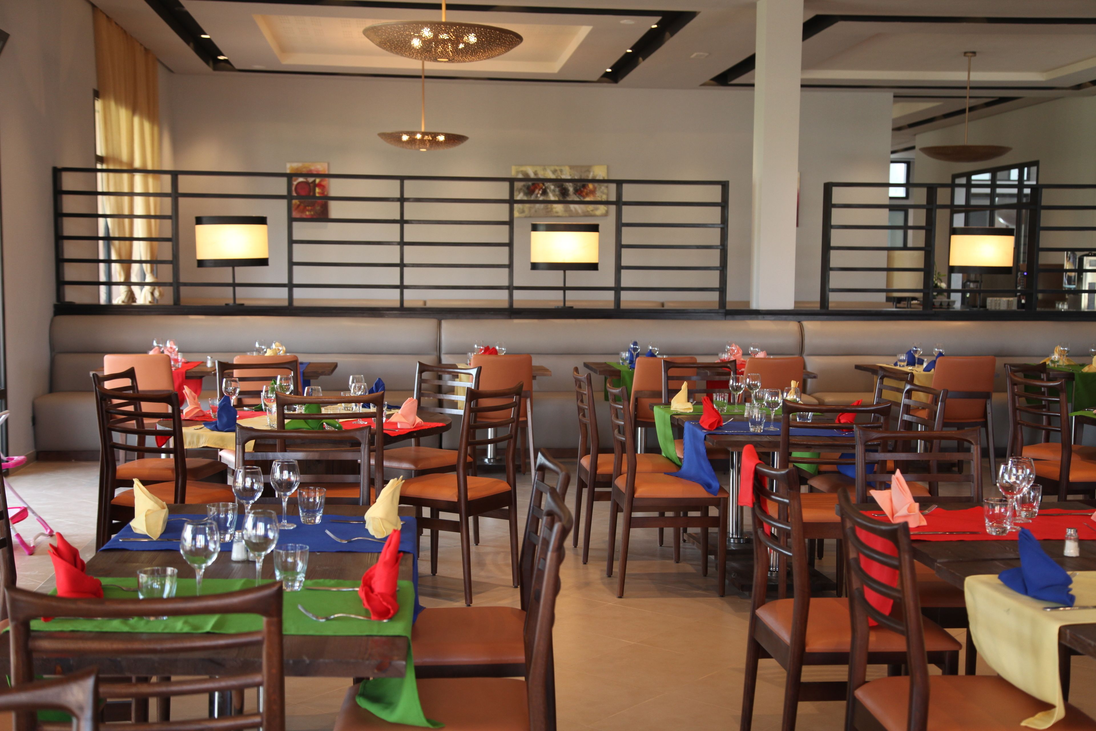 A restaurant with multiple tables and chairs, each set with wine glasses and napkins.