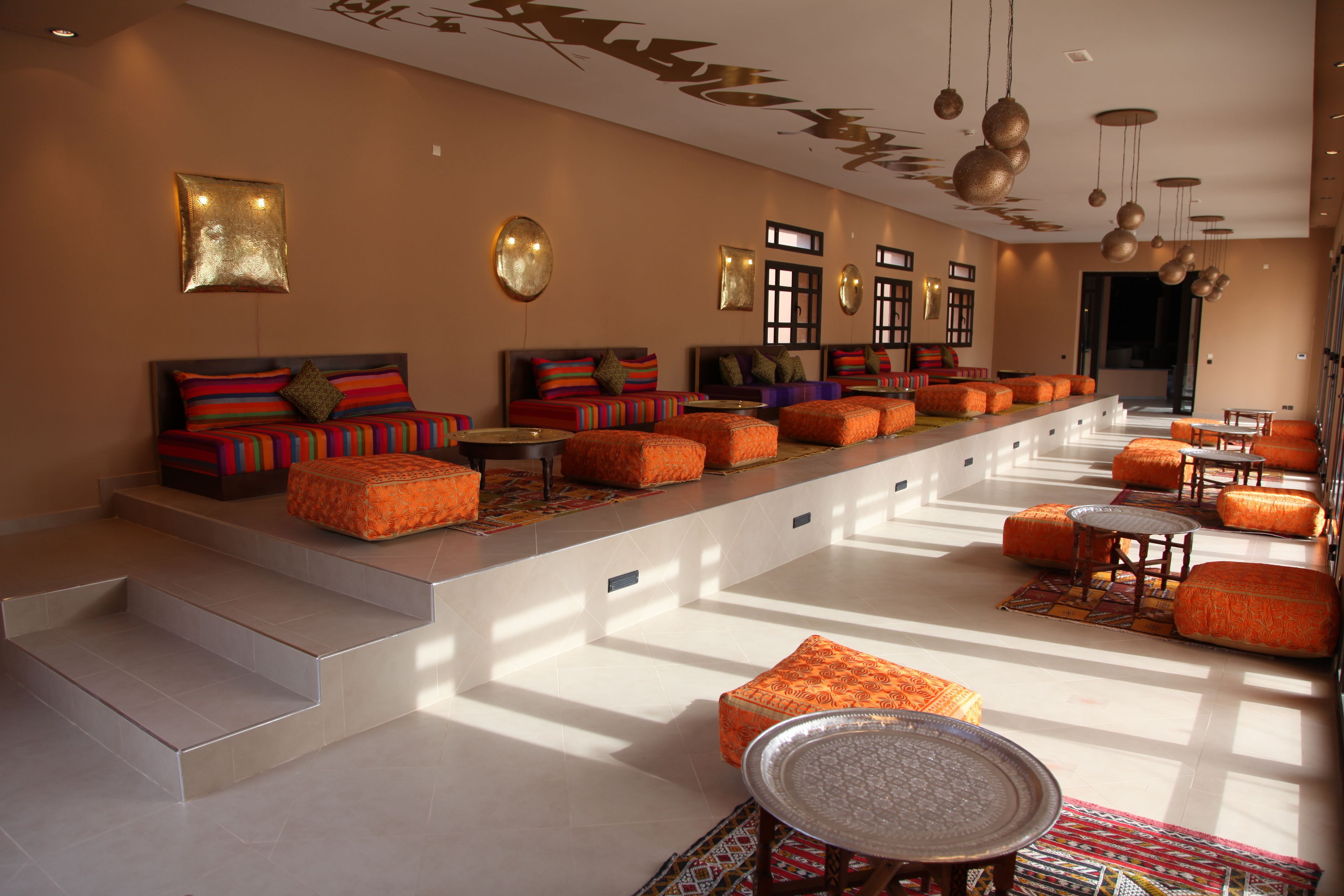 A spacious lounge area with tiered seating, a central coffee table, and a decorative wall piece.