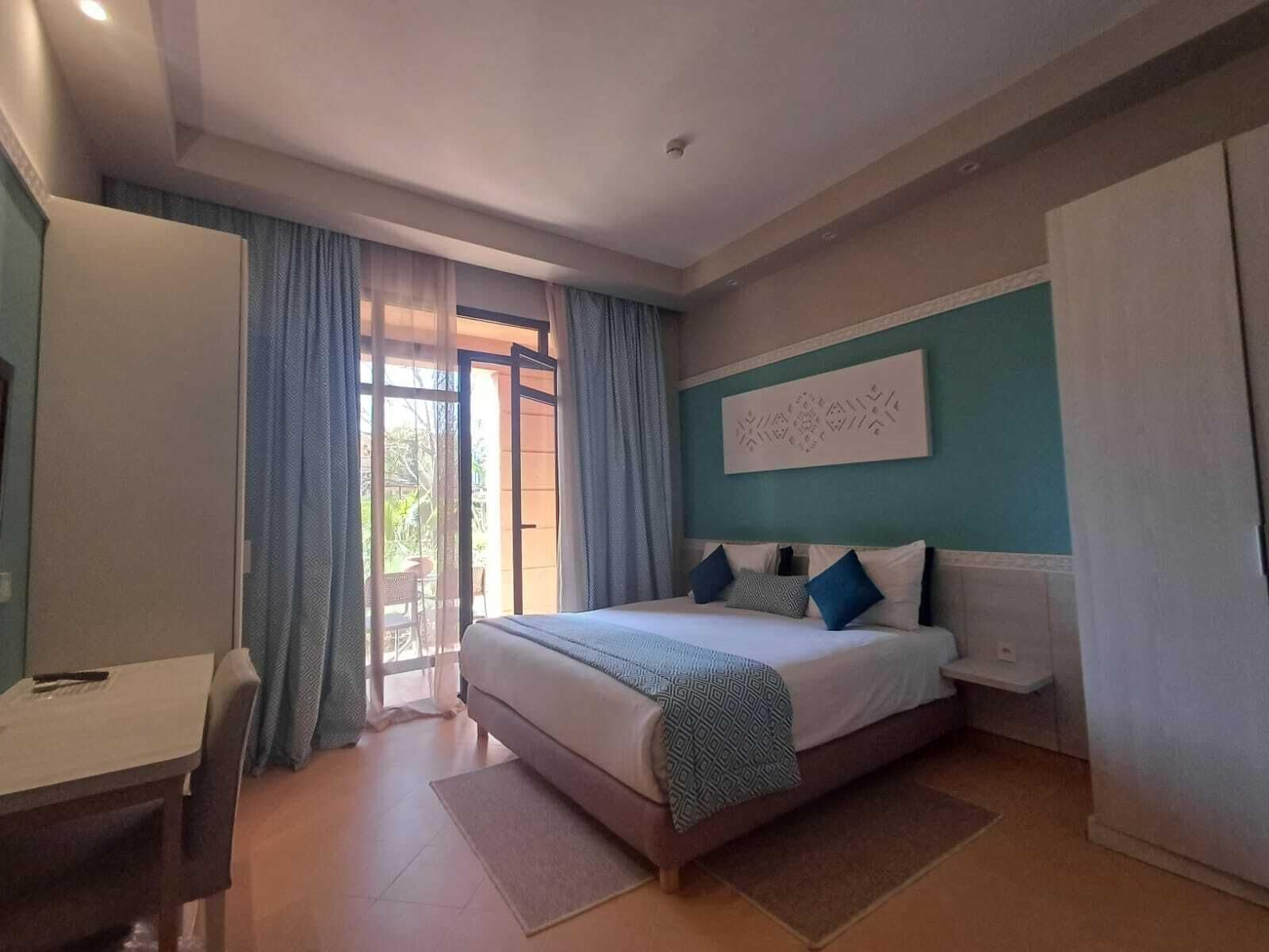 Un dormitorio con cama, escritorio y vistas a través de una puerta de cristal.