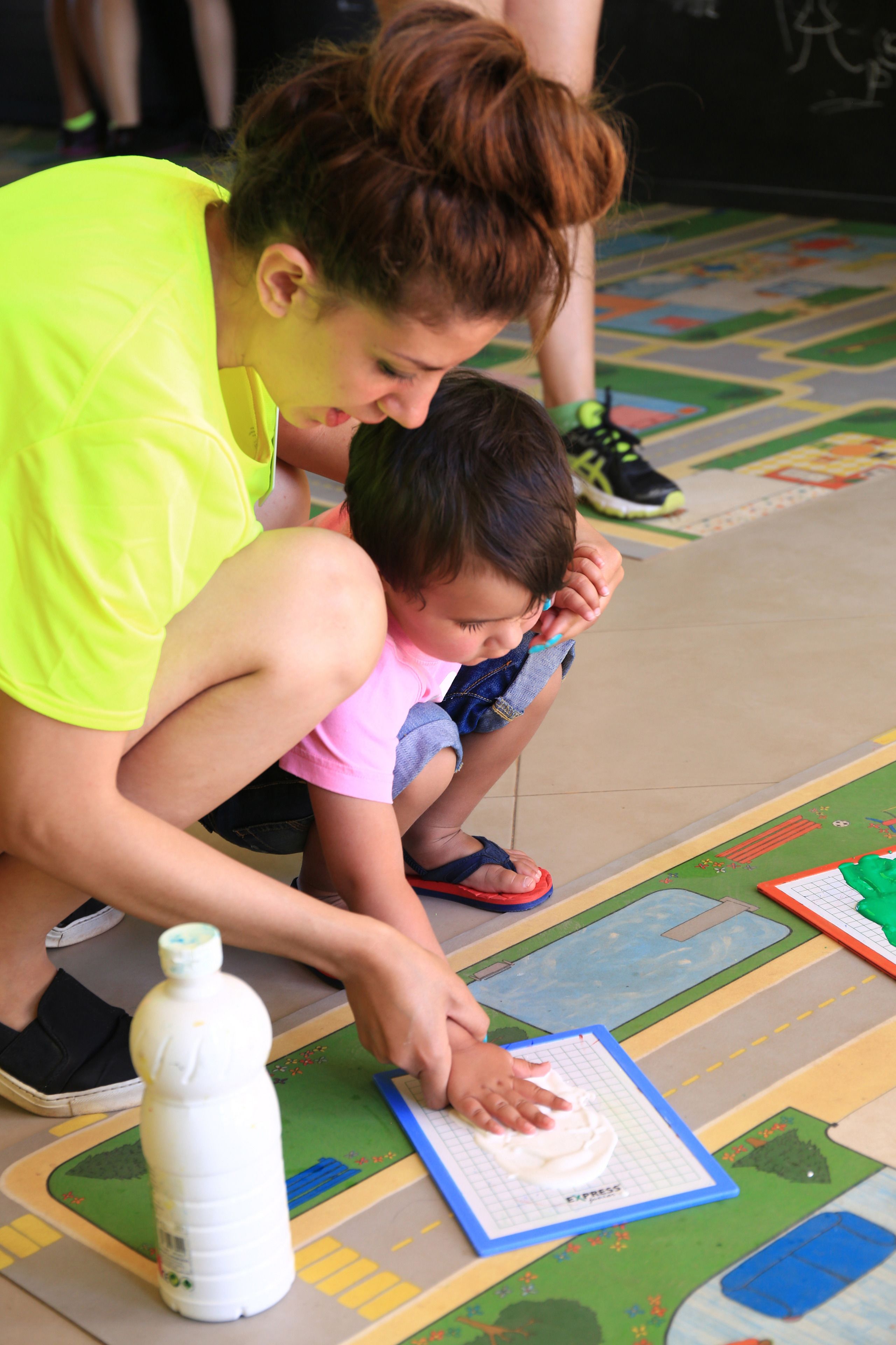 Un enfant et un adulte participaient à une activité manuelle sur un tapis de jeu coloré.