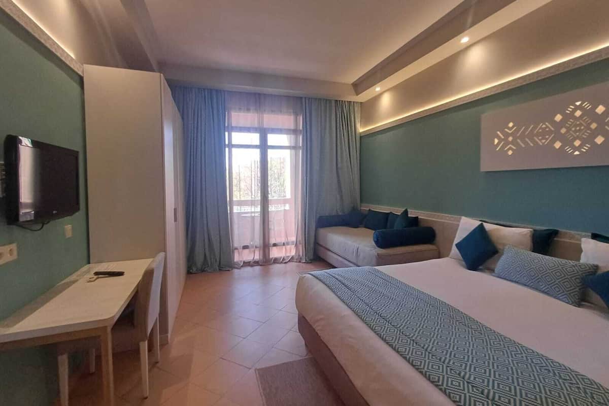 A hotel room with a bed, a desk, and a TV.