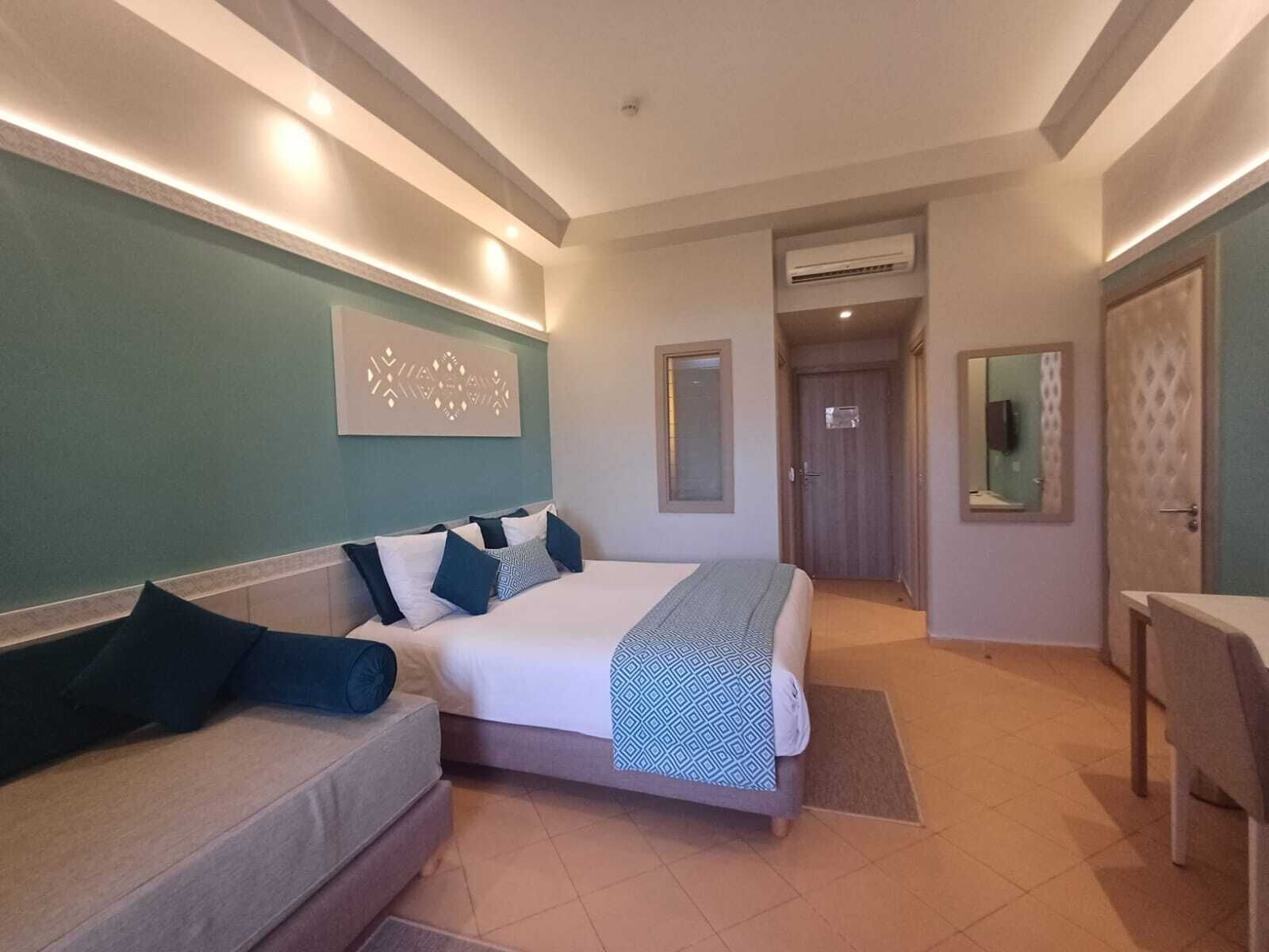 Una habitación de hotel con cama, sofá, escritorio y puerta al baño.