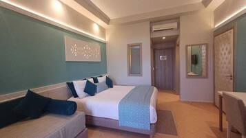A hotel room with a bed, a sofa, a desk, and a bathroom door.