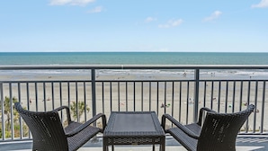 A balcony with wicker furniture overlooking a beach. - Oceans One Resort (Myrtle Beach)