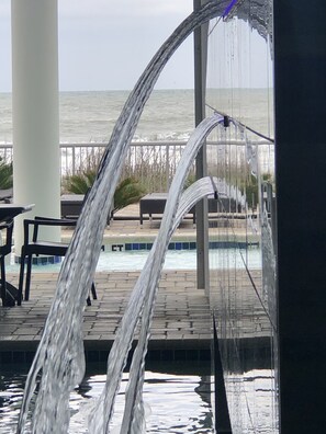 A pool area with a water feature and a view of the ocean.