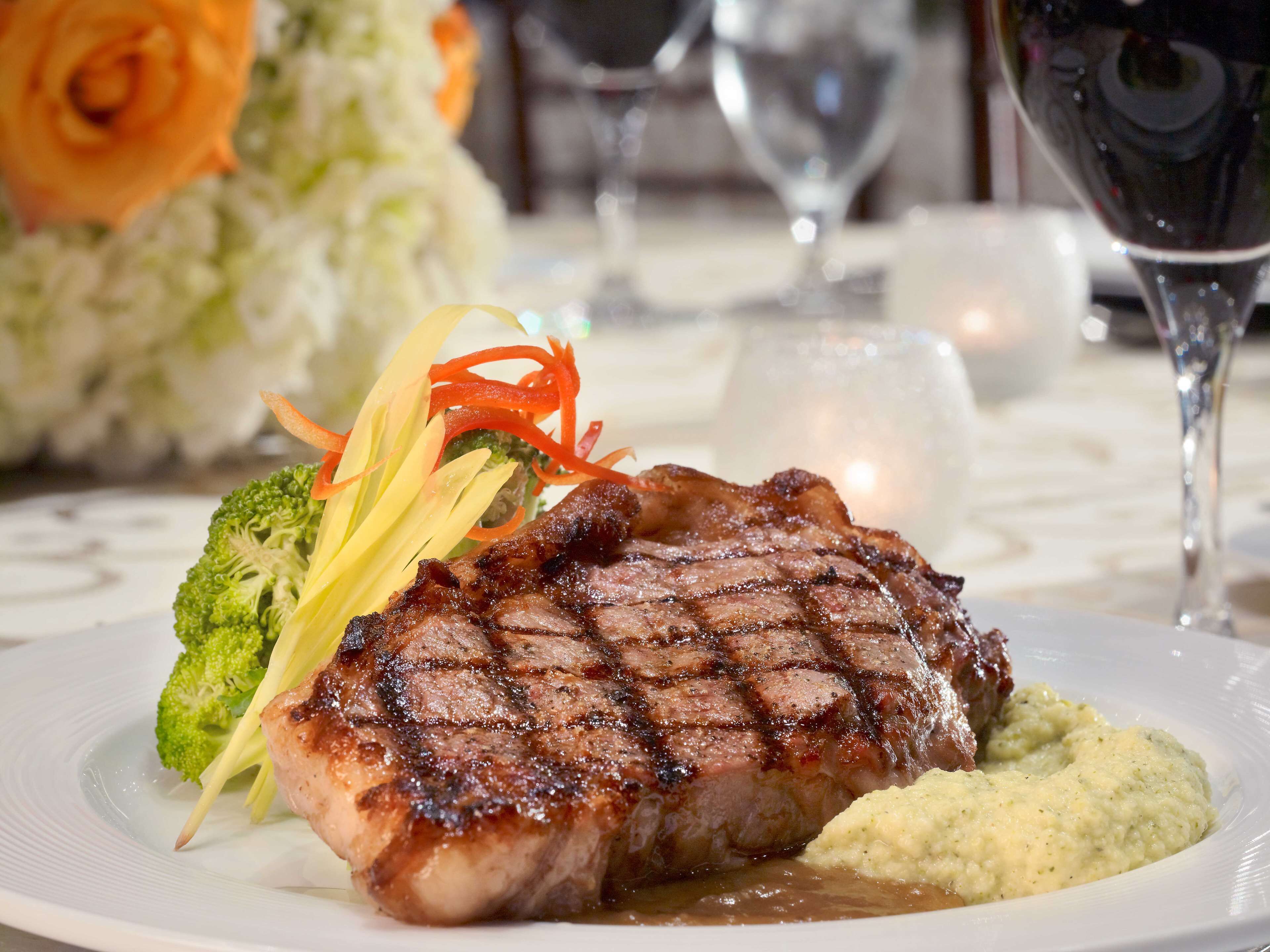 A plate with grilled steak, broccoli, and a creamy sauce.