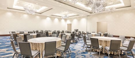 A conference room with round tables and chairs, a patterned carpet, and a ceiling with hanging lights.