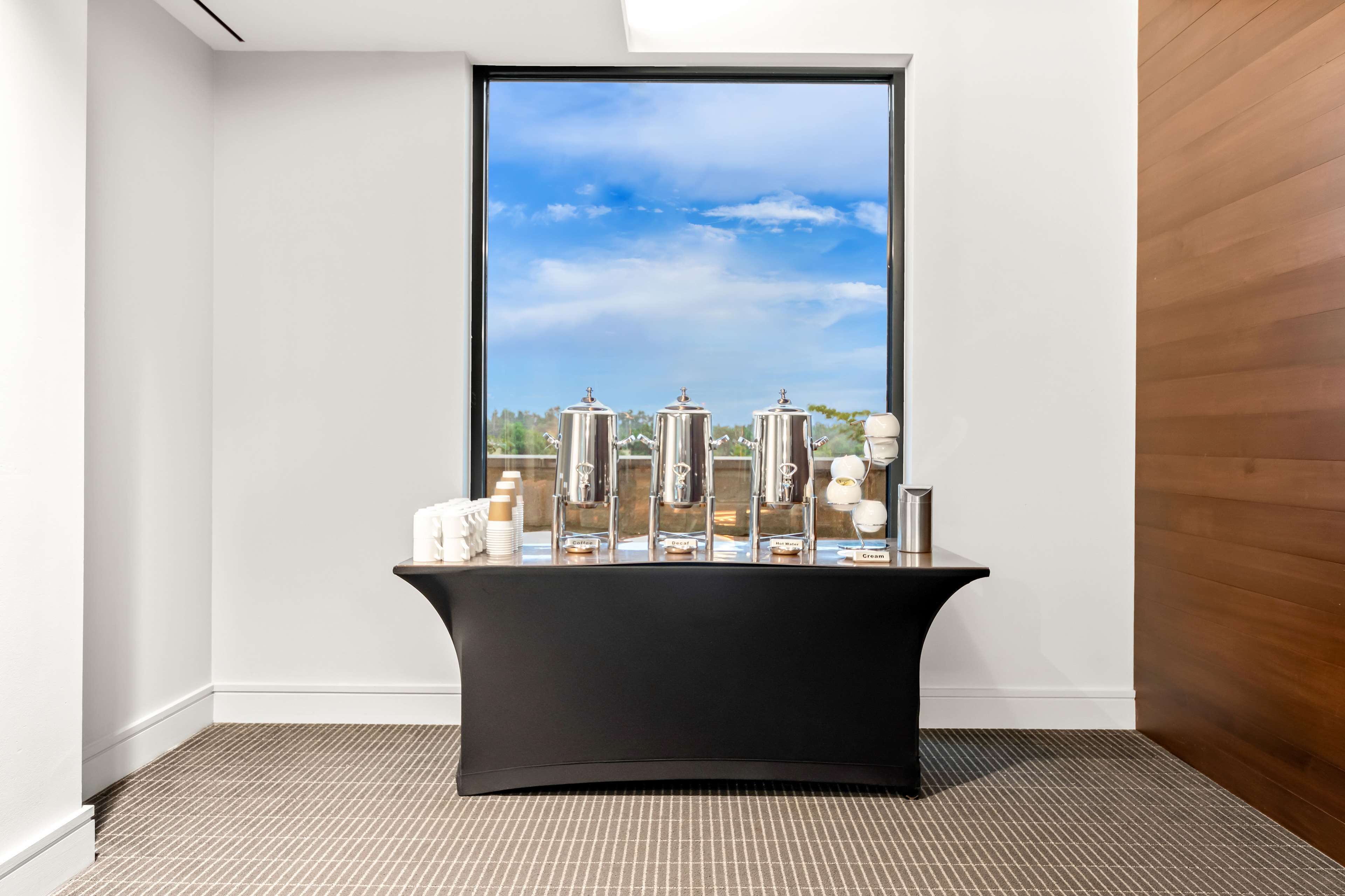 A modern room with a black console table, a large window with a city view, and a wooden wall.
