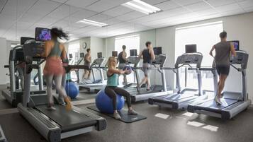 Un gimnasio con cintas de correr, pelotas de ejercicio y espejos.