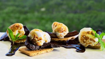 A dessert with marshmallows, chocolate, and mint leaves on a plate.