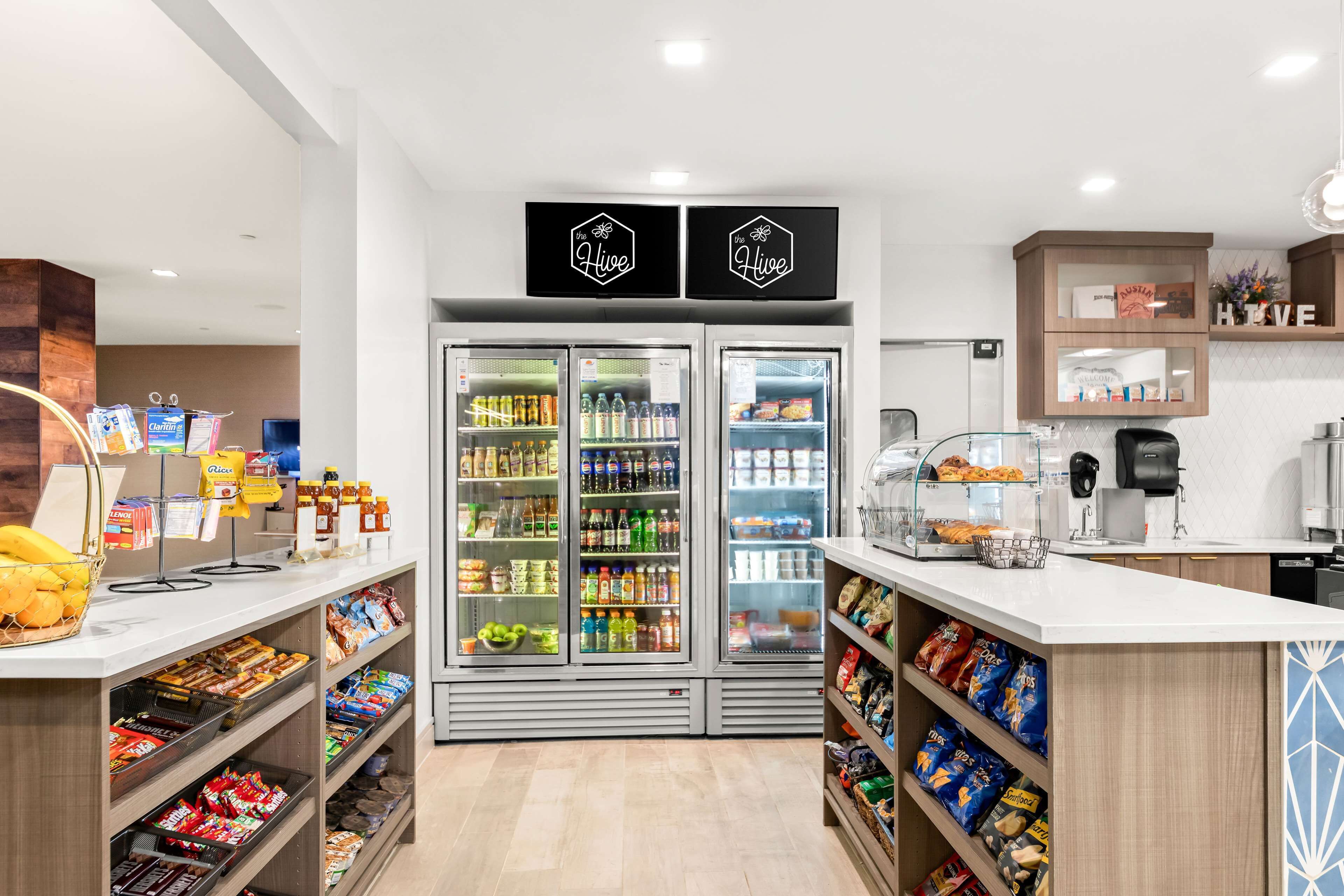 A modern self-service kiosk with refrigerated beverage dispensers, snack shelves, and a coffee machine.