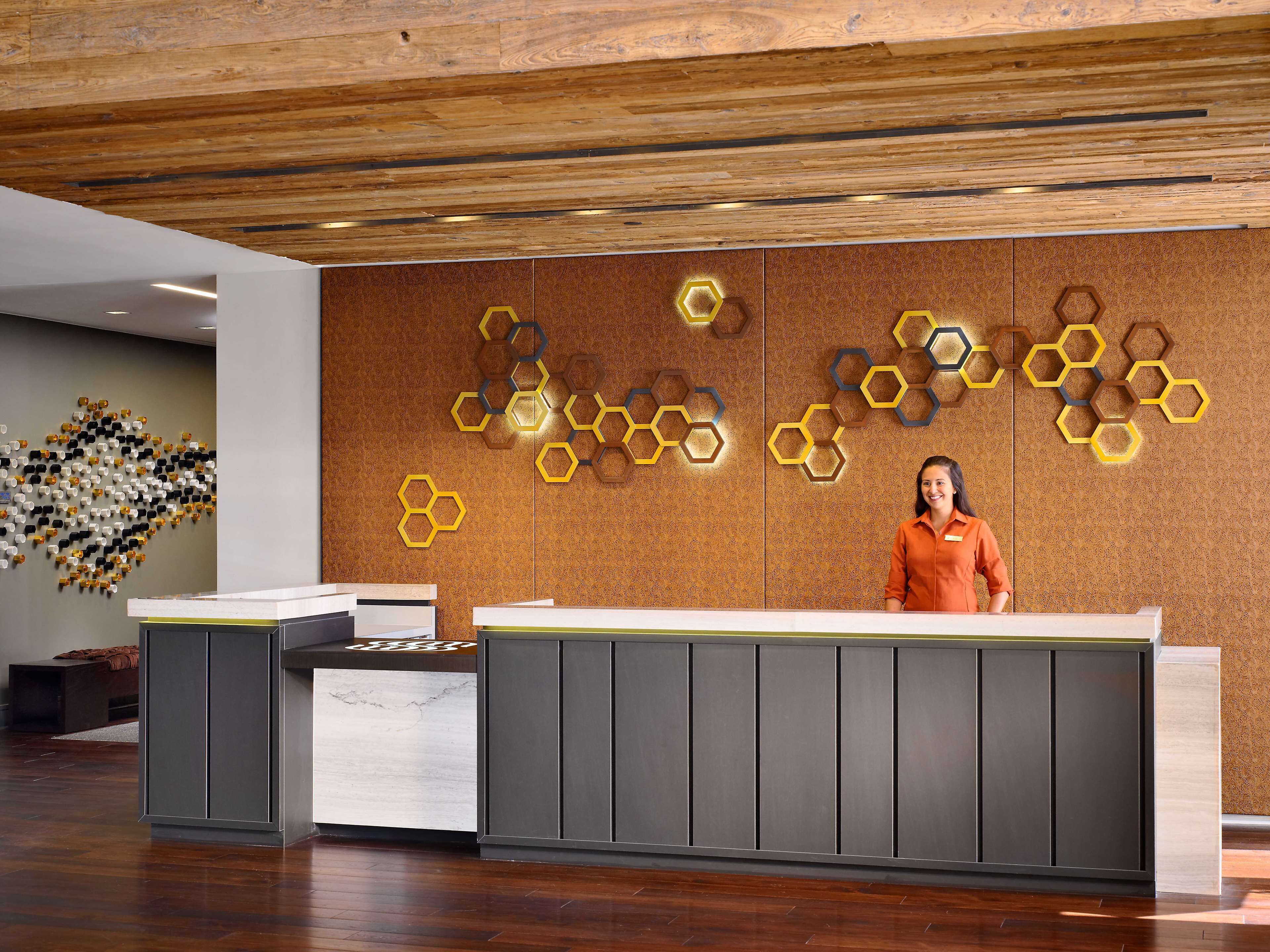 Una recepción con diseño moderno, techo de madera y pared con patrones hexagonales.