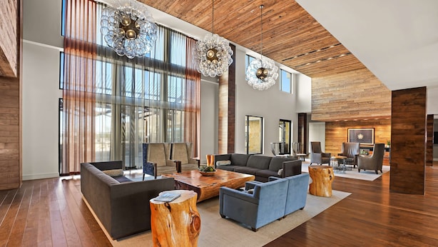 A spacious living area with a modern design, featuring a large sofa, a coffee table, and a wooden accent piece. - Sonesta Bee Cave Austin Hill Country (Austin)