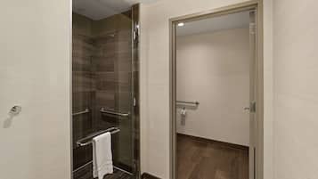 A modern bathroom with a glass shower enclosure, a towel rack, and a door leading to another room.