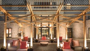 A spacious outdoor seating area with multiple sofas and chairs, a wooden pergola structure overhead, and potted plants. - Sonesta Bee Cave Austin Hill Country (Austin)