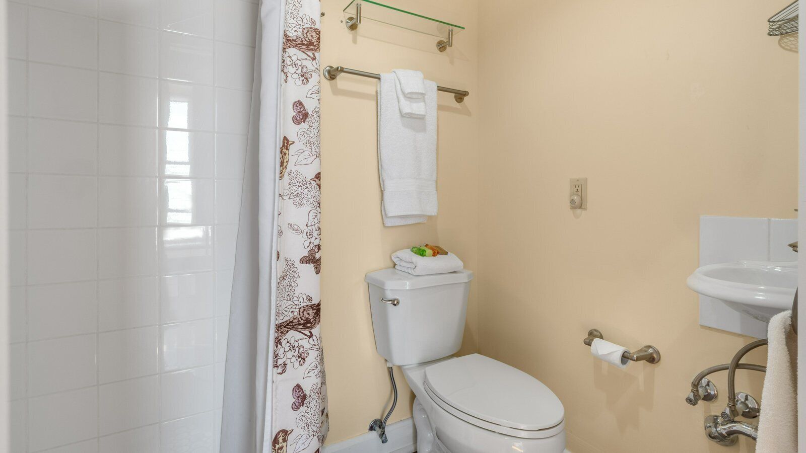 Un baño con inodoro, lavamanos y cortina de ducha.