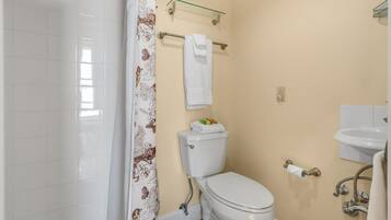Un baño con inodoro, lavamanos y cortina de ducha.