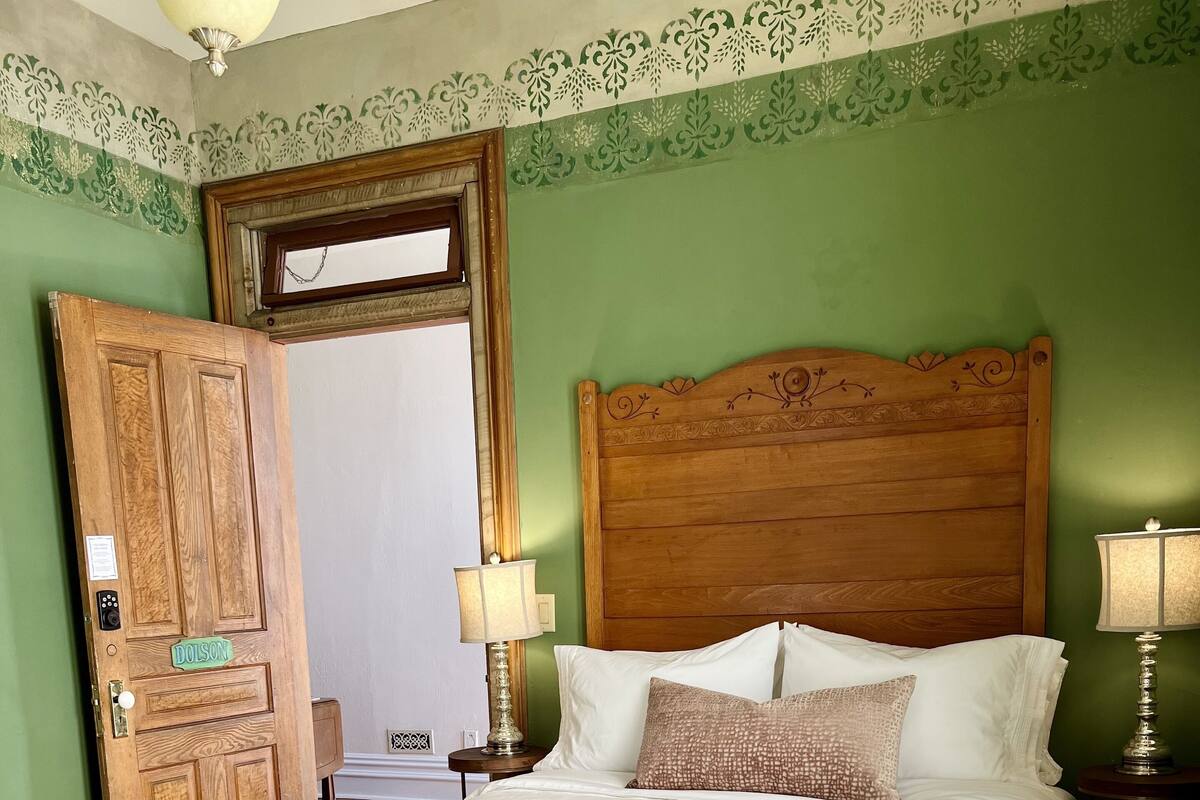 Una cama bien hecha con ropa de cama blanca, cabecera de madera y dos lámparas de noche.