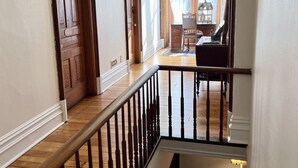 A wooden staircase with a black railing leading to a second-floor landing. - The Woodbridge House (Kingsville)