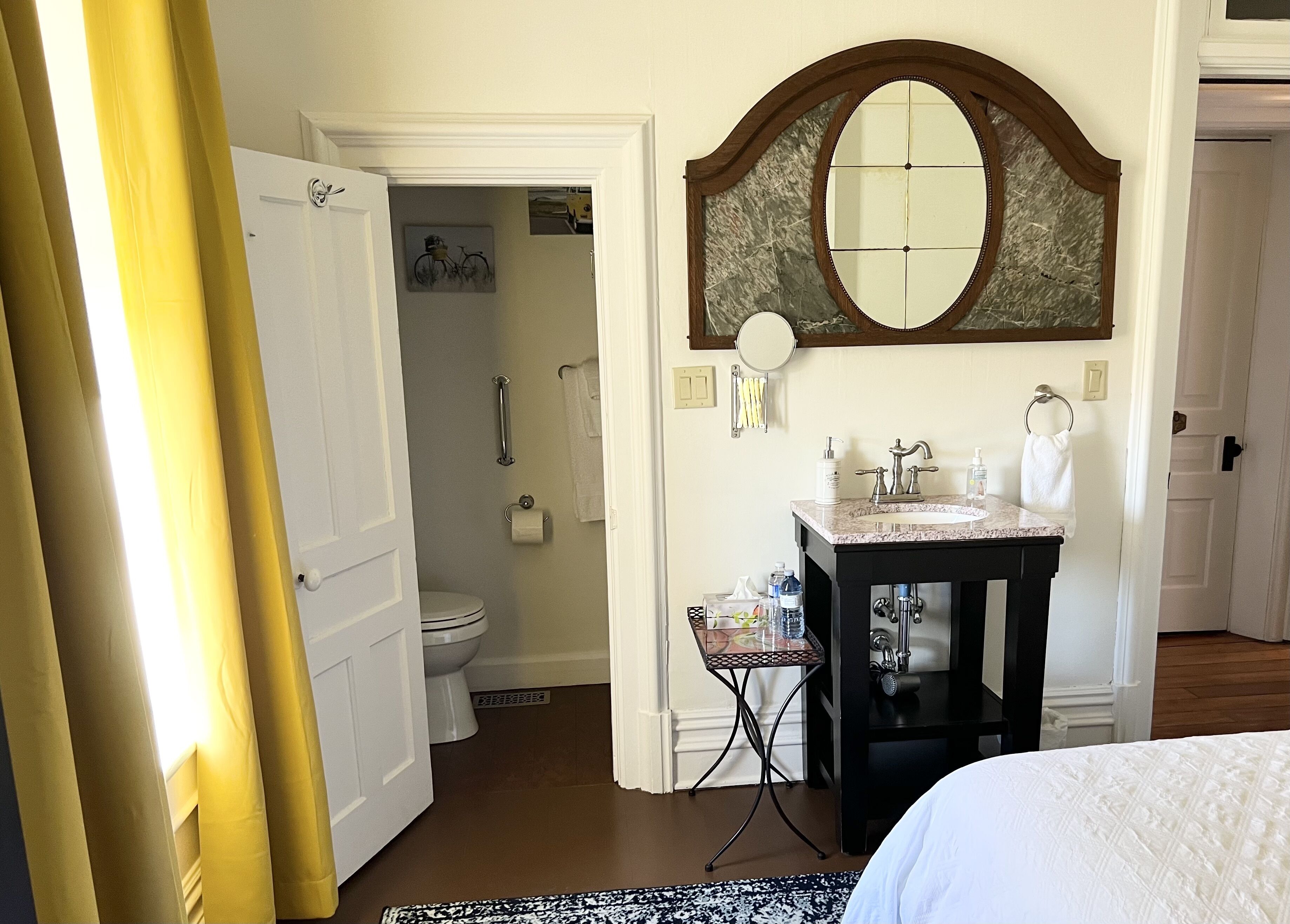 A hotel bathroom with a toilet, sink, and mirror.