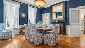 A dining room with a wooden table and chairs, a chandelier, and a fireplace. - The Woodbridge House (Kingsville)