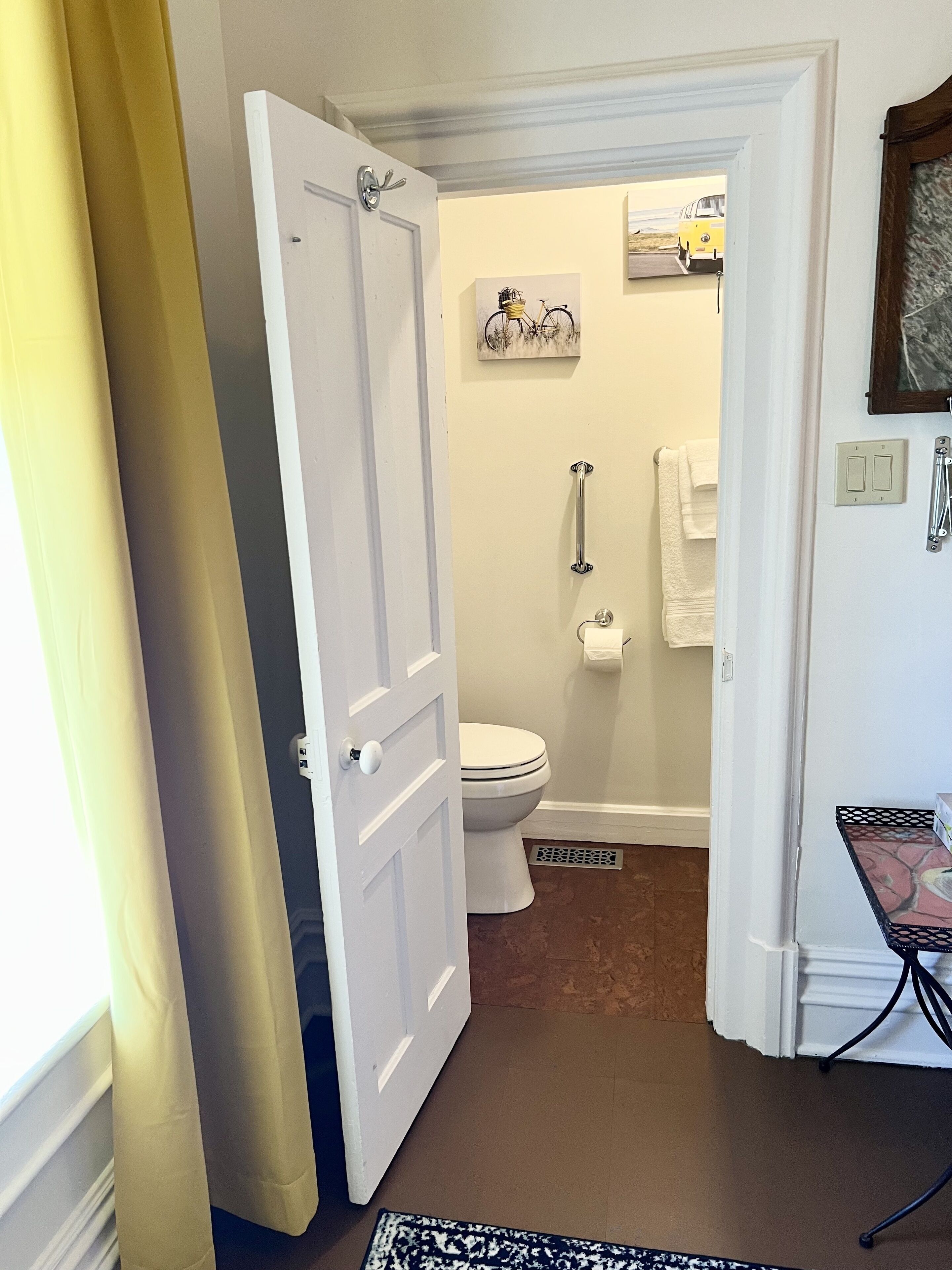 Een badkamer met een wit toilet, een douche, een handdoekhouder en een klein tafeltje met een decoratief object.