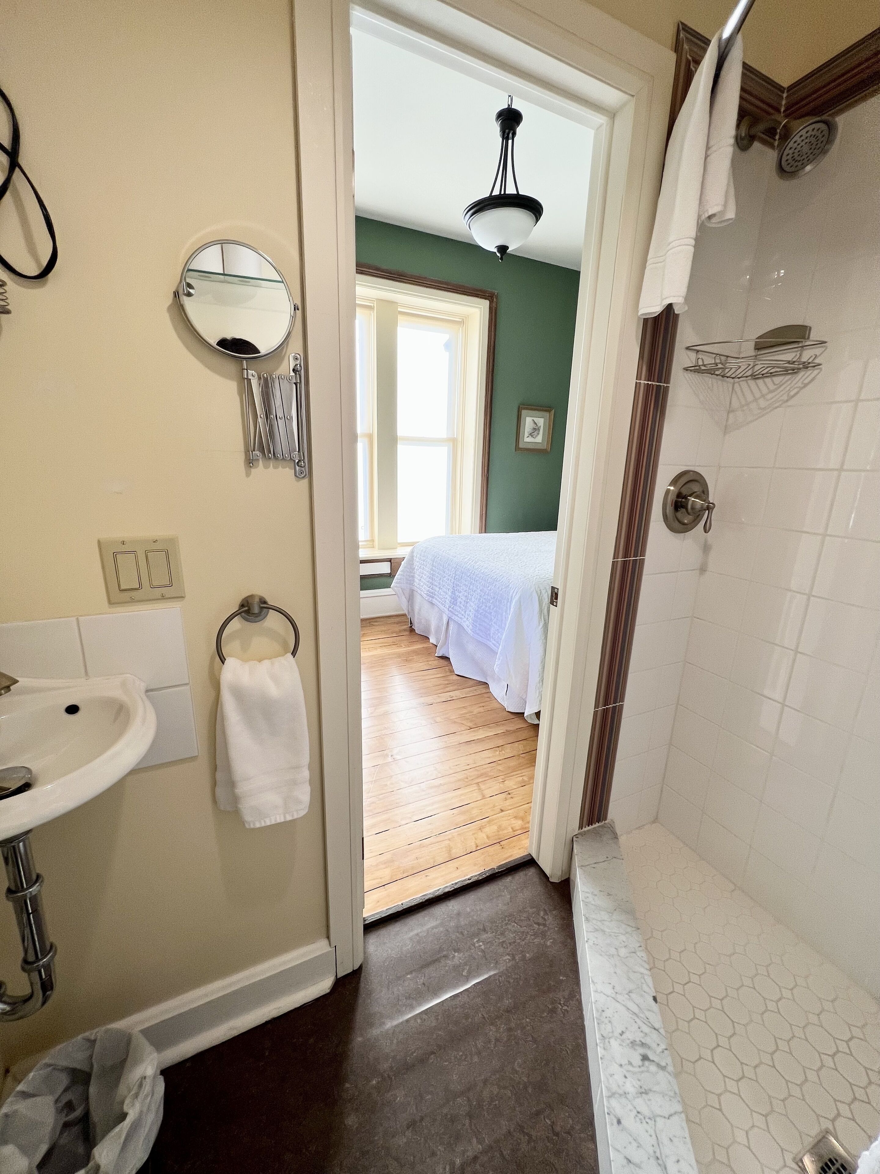 Un baño con lavamanos, espejo, toallero y zona de ducha.