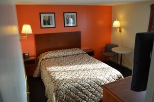 A hotel room with a bed, two bedside lamps, a small table, and a TV.